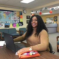 Nadia In A Classroom Working On A Laptop