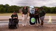 4 people with CSI mascot dolphin in front of the fountain