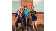 A group of people holding a root of Japaneese Knotweed and shovels