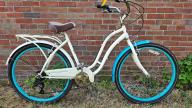 A white cruiser bike with handle brakes and back storage