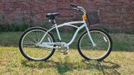 A Radeberger Pilsner white bike with a black seat, with gears, black wheels, curved handle bars and pedal breaks