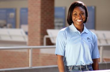 Female Admissions Advisor in blue shirt standing inside campus building