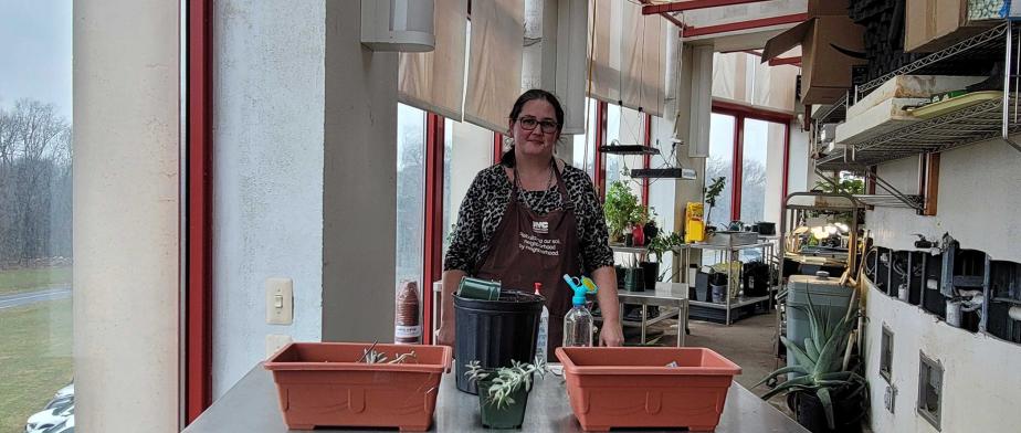 A woman  in a green house with a lot of planters