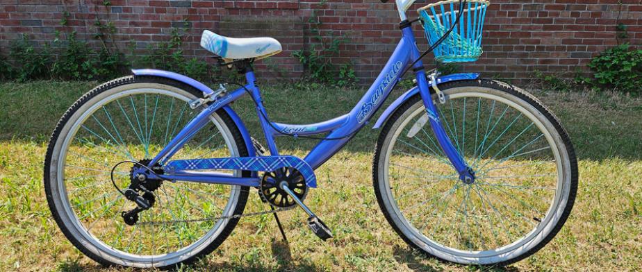 A blue cruiser bike with white rims, gears and no handbreaks 