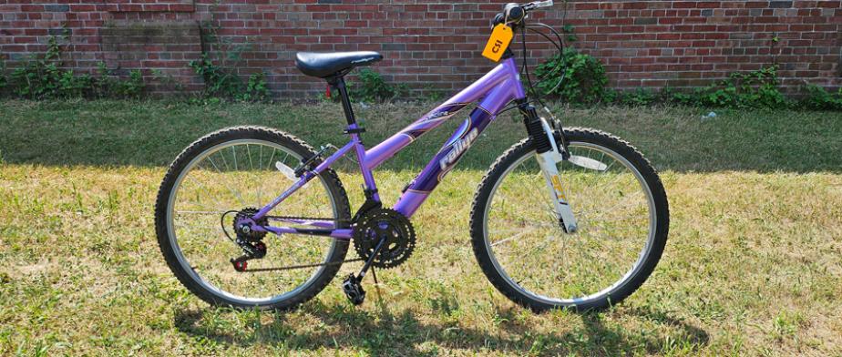 A Rallye branded light purple bike with a black seat, straight handle bar, b lack wheels with handbreaks and gears