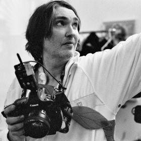 The professor is holding a camera, and looking up The professor is holding a camera, and looking up