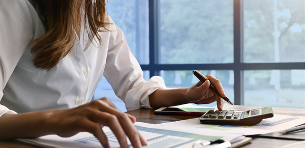 Woman’s hands using a calculator and going through paper on desk