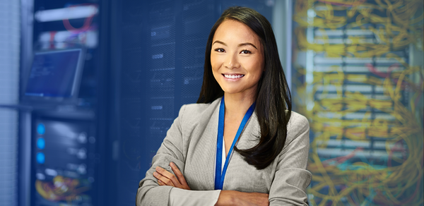 Young woman in suit smiling in front of network servers in office