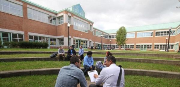 Students Studying Behind Building 1P On A Grassy Lawn
