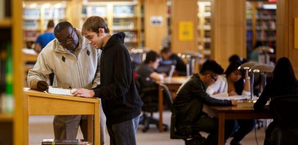 two males standing in library