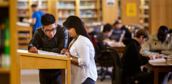 2 students standing in the library