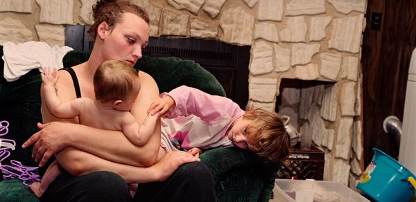 a color photograph of a young mother and her babies on a couch