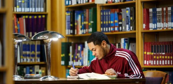 male student sitting at desk in the library