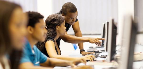 students looking at PC monitor in classroom