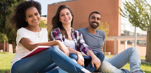 students sitting on grass on campus