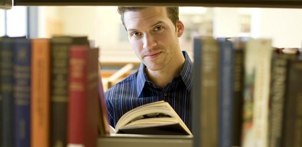 Faculty Center Student Peaking Through Book Isle 