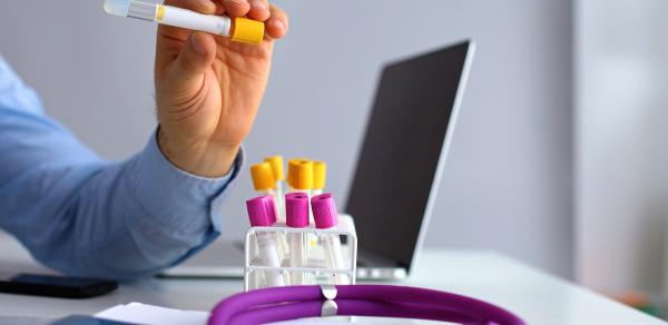 Vial of medicine on a desk with a laptop in the background PharmD