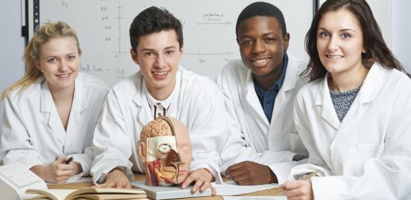 Students In Lab Coats Sitting at Table