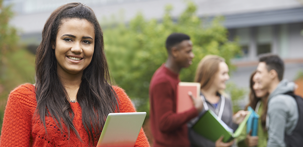 female student holding a book with 2 male students in background