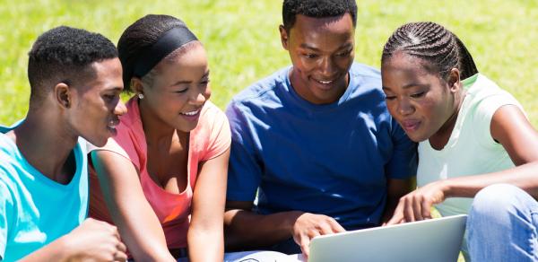 Students Outside Helping Each Other On A Laptop