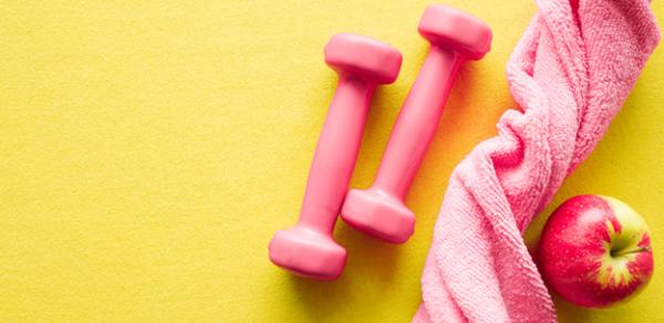 pink dumbbells, pink towel, an apple