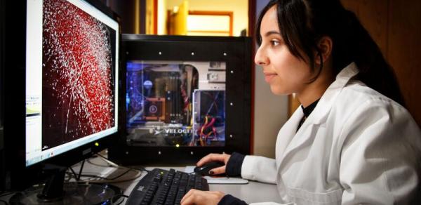 women sitting at monitor in white lab jacket