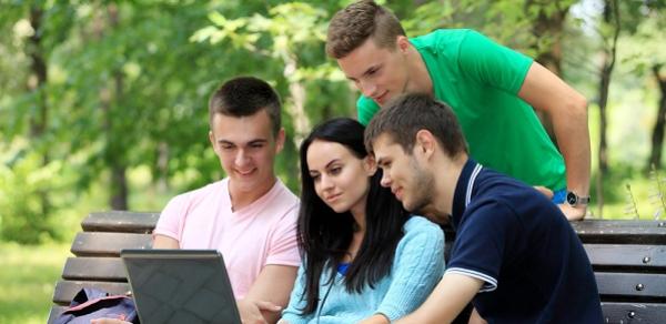 Three Students On Bench With One Leaning Over Looking