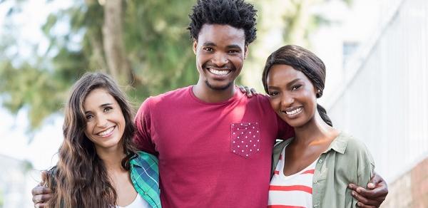 Three Students Smiling With Arms Around Each Other