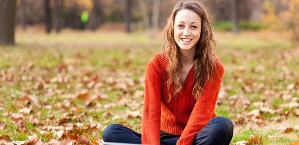 Student Sitting In Pile Of Leafs Outside