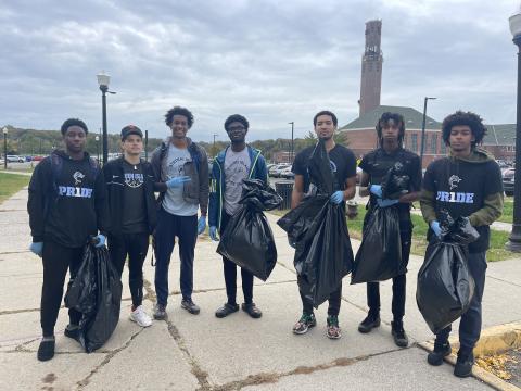 campus cleanup athletes in uniforms 8 student athletes wearing their CSI uniform are standing in front 1 R Recreation building. They are holding black garbage bags filled with trash they picked up on campus.