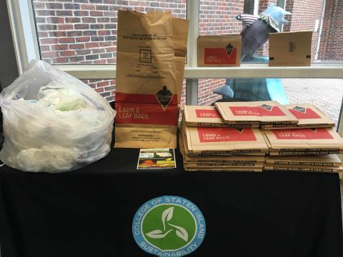 Bag drive table with paper leaf bags and donated plastic bags on top of the table.