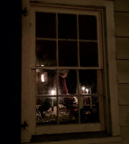 A woman working by candle light in Historic Richmond Town
