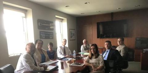 Picture of President's office cabinet sitting around oval table with the shades up letting daylight in.