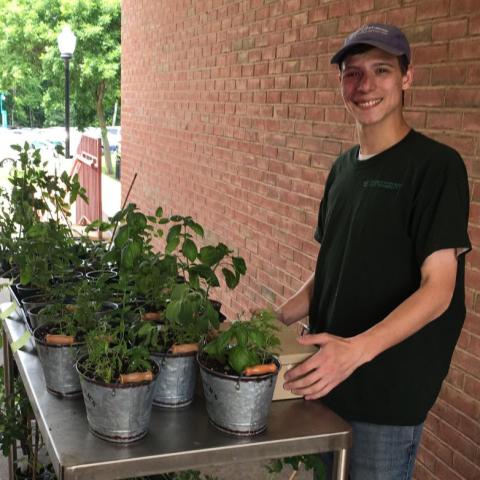 Photo of Marc Girgenti standing next to a table with potted plants