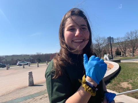 A person with long hair wearing a blue glove and smiling.​