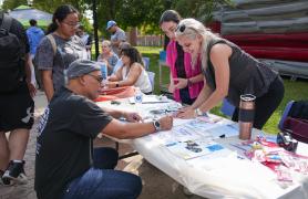 group of students  with an instructor at the activity table outdoors