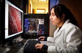 girl in white lab coat looking at PC