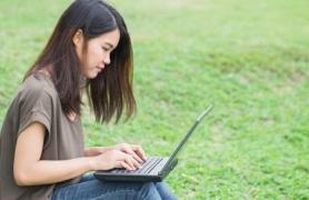 Student alone on grass with laptop