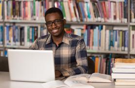 Student At Library Desk On Laptop